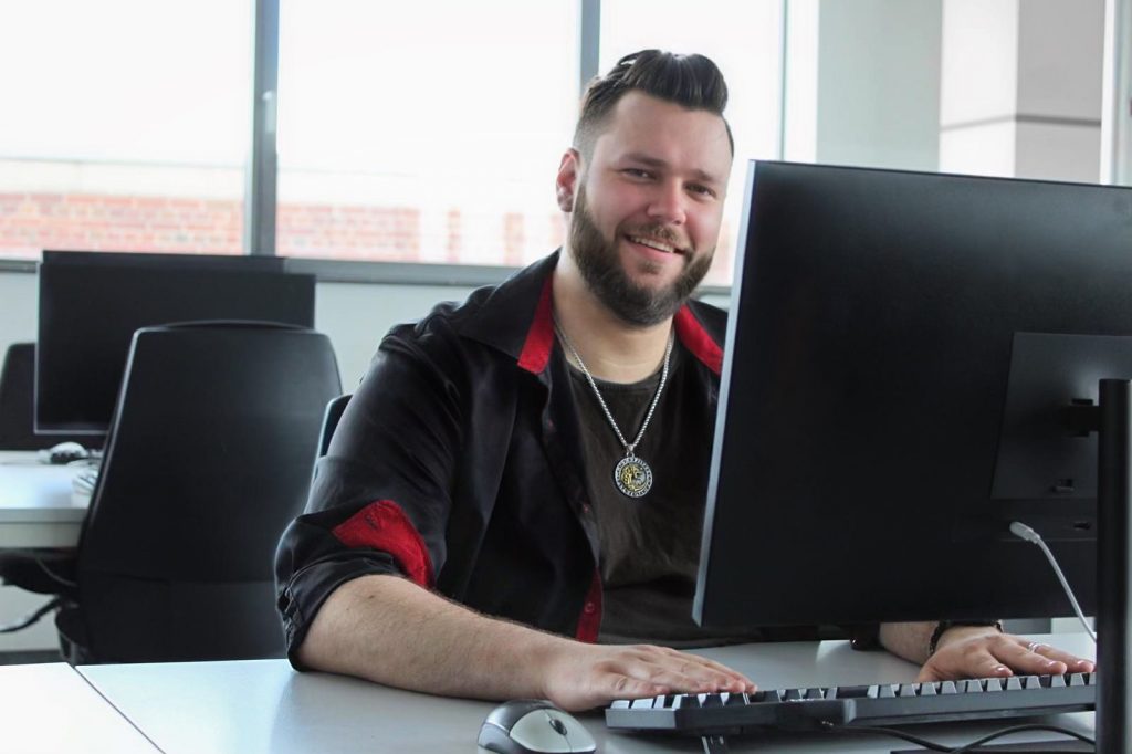 Nils Dozent sitzt vor Computer und schaut in die Kamera